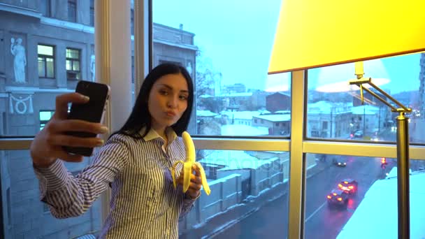 귀여운 여자는 바나나를 들고 고 휴대 전화에 촬영 — 비디오