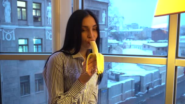 Aranyos lány szépen eszik egy banánt és egy mosolygó — Stock videók