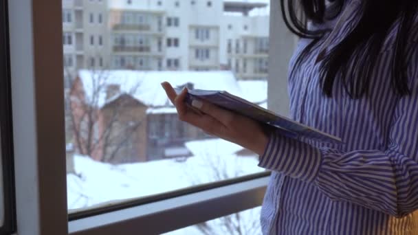 Una chica de pie, sosteniendo un bloc de notas en la mano y escribe — Vídeo de stock