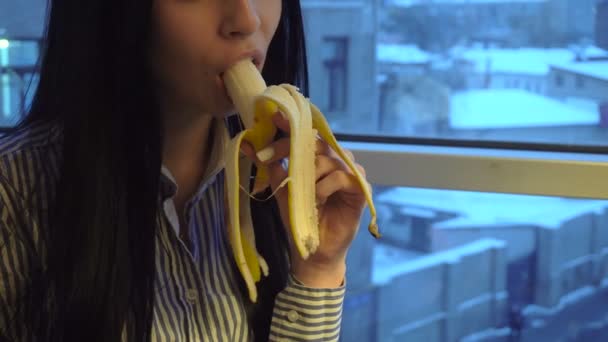 Крупным планом сексуальная девушка с темными волосами ест банан — стоковое видео