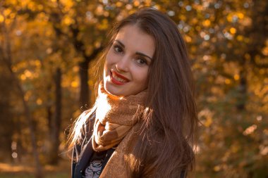 Kırmızı dudaklar ile genç kız parkta duruyor ve gülümsüyor