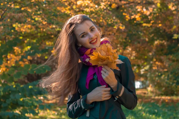 Mooi meisje staat op de straat en houdt de bladeren in de handen van — Stockfoto