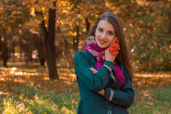 Schattig meisje staat in de herfst Park met een takje Rowan in haar hand — Stockfoto