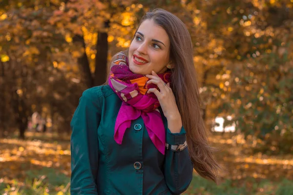 Chica joven con un pañuelo rosa alrededor de su cuello se para en el parque — Foto de Stock