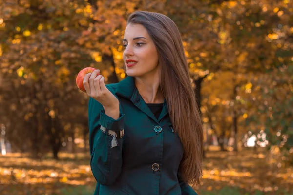 Linda gir fica no parque olha para longe e mantém a Apple na mão — Fotografia de Stock