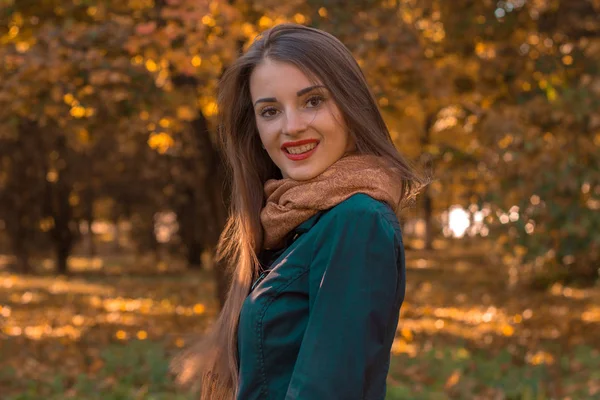 Симпатичная девушка стоит в осеннем парке и улыбается — стоковое фото