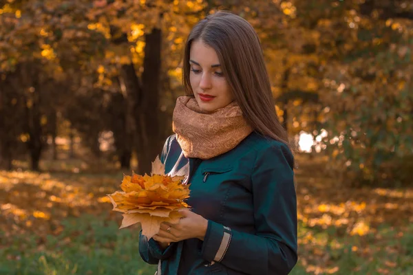 若い女の子が公園に立って、葉の花束を保持します — ストック写真