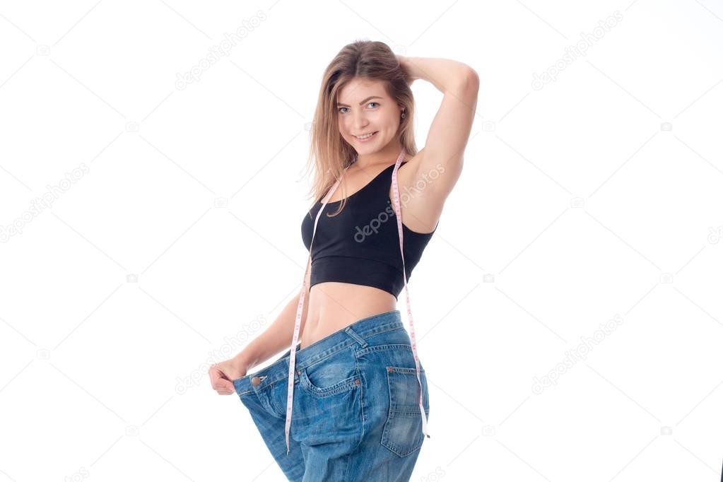 slim girl stands in a large wide jeans lifting arm