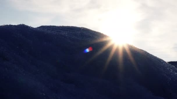 Sonnige, helle Strahlen scheinen durch den kalten, schneebedeckten Berg — Stockvideo