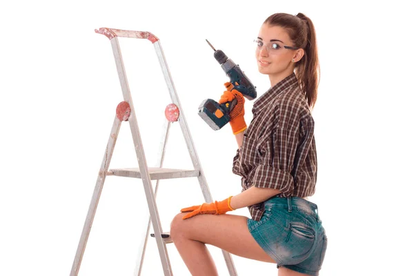 Молодая красивая строительница девушка в форме с дрелью делает ремонт изолирован на белом фоне — стоковое фото