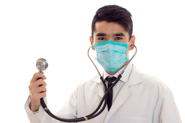 Studio ritratto di medico maschio in uniforme e maschera con stetoscopio nelle mani posa isolato su sfondo bianco — Foto Stock