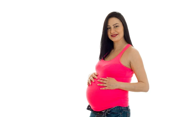Unga gravid brunett kvinna i rosa skjorta poserar isolerad på vit bakgrund — Stockfoto
