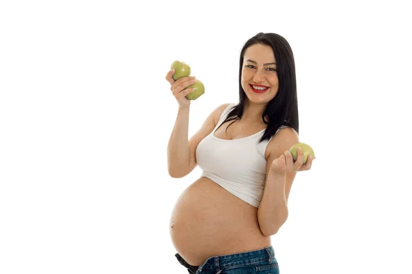 Joven embarazada morena posando con manzanas verdes aisladas sobre fondo blanco — Foto de Stock