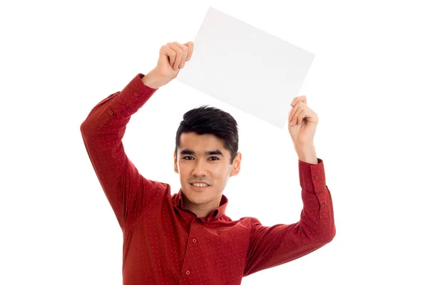 Jovem morena alegre homem em t-shirt vermelha posando com cartaz branco isolado no fundo — Fotografia de Stock
