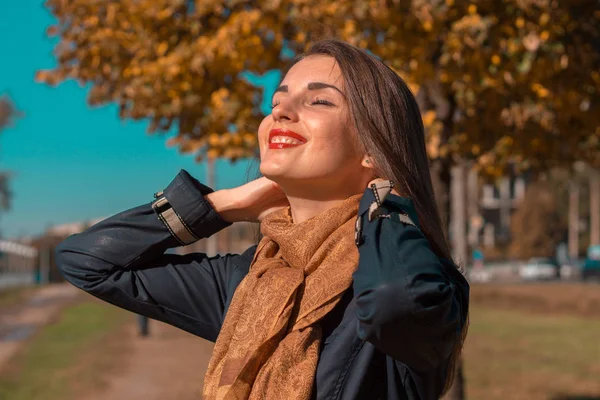 Belle fille en automne Parc garde les mains derrière le cou fermé ses yeux et sourit — Photo