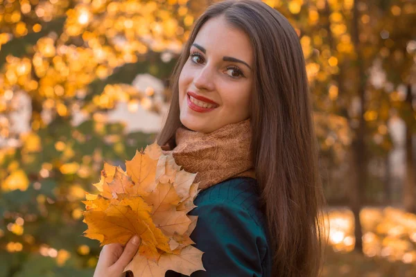 Mooi meisje met rode lippen draaide haar hoofd glimlachend en houdt een blad — Stockfoto