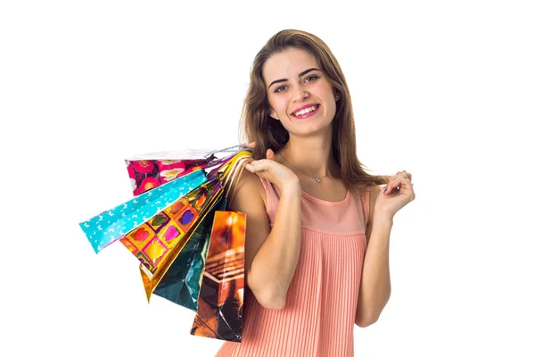 Jovem menina bonita mantém em diferentes sacos de ombro coloridos com presentes e sorrindo — Fotografia de Stock