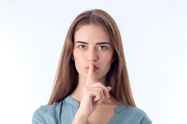 Young girl looks straight and keeps the finger to mouth — Stock Photo, Image