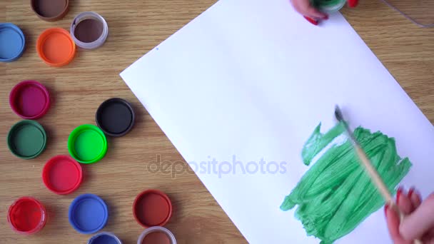 El artista dibuja una pintura verde sobre una hoja de papel — Vídeo de stock