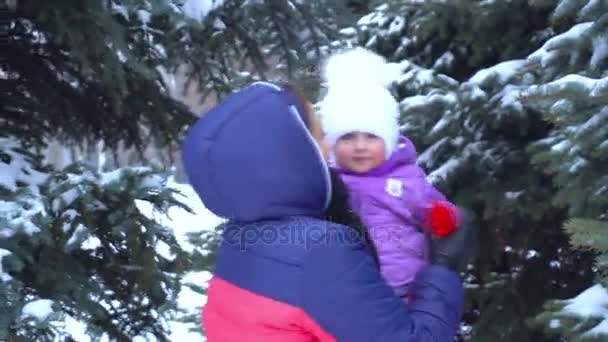 Mãe vira o bebê em seus braços perto de árvores nevadas — Vídeo de Stock