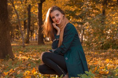 siyah bir pelerin güzel genç kız sonbahar parkta çim oturur