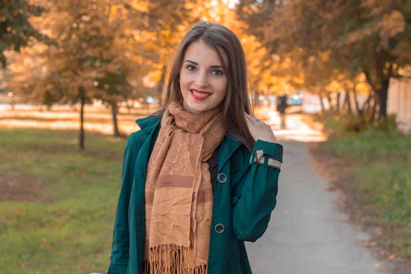 Улыбающаяся девушка в теплом шарфе стоит на улице смотрит направо и — стоковое фото