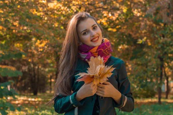 Jovem bonito menina com cabelos longos está sorrindo e segurando uma folha — Fotografia de Stock