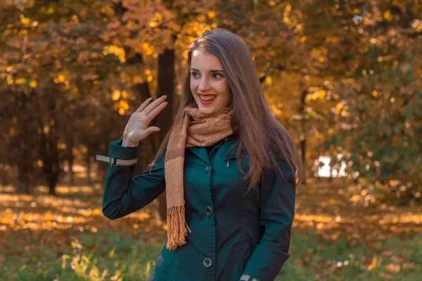 Sorrindo jovem mulher com um cachecol nos ombros de stands no parque e sorri — Fotografia de Stock