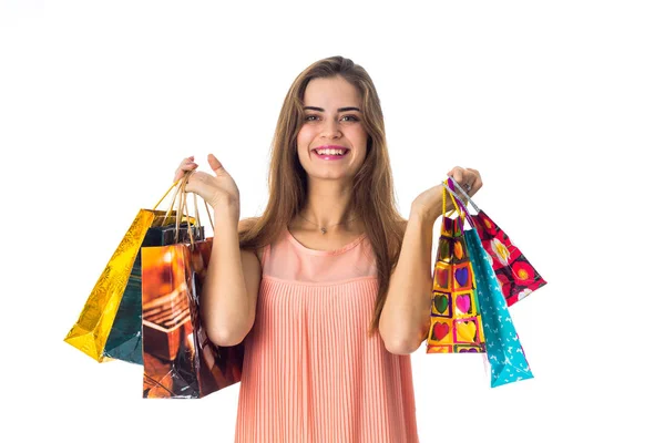 Bela menina feliz olha em linha reta e levantada nas mãos de muitos sacos multicoloridos de lojas — Fotografia de Stock