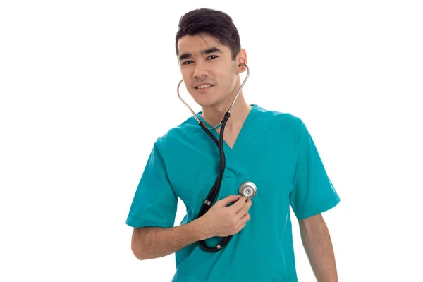 Jeune homme beau médecin posant avec stéthoscope en uniforme isolé sur fond blanc en studio — Photo