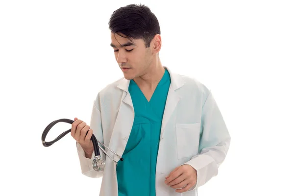 Young man doctor posing in uniform with stethoscope isolated on white background in studio — Stock Photo, Image