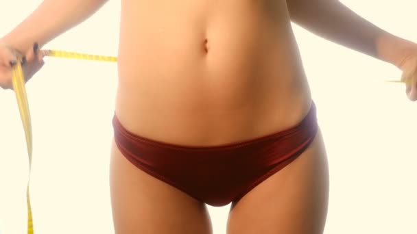 Beautiful slim woman in red sports panties measure her waist in studio — Stock Video