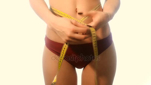 Jeune fille mince en culotte de sport rouge mesurer sa taille en studio — Video