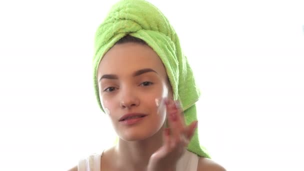 Girl with towel on the hair with both hands causes the cream on her face — Stock Video