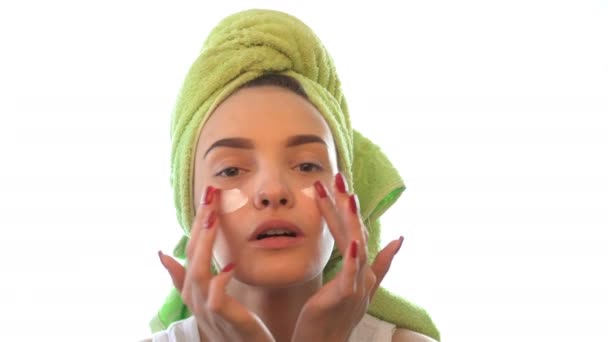 Молода дівчина з рушником на голові викликає крем для очей — стокове відео