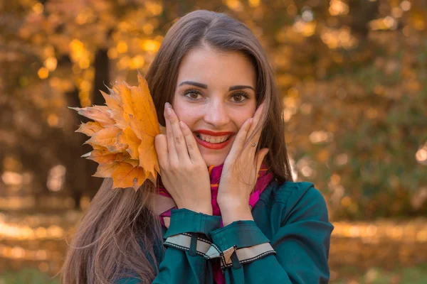 Joven chica atractiva con lápiz labial rojo sonríe y sostiene la palma de su mano cerca de la cara de cerca — Foto de Stock