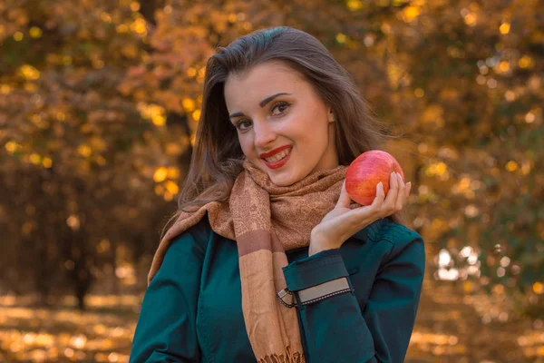 Piękna dziewczyna w szał brązowy szalik trzyma jabłko i uśmiechający się bliska — Zdjęcie stockowe
