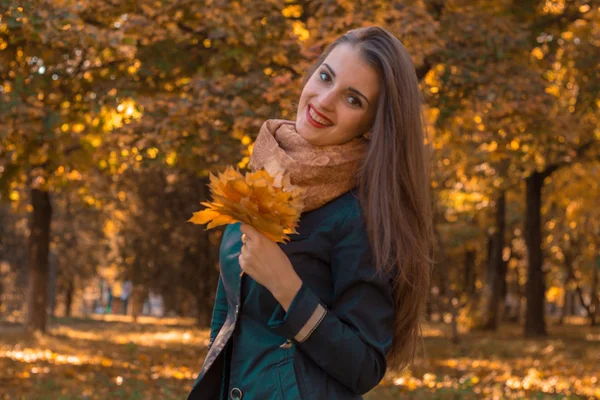 Jovem alegre no parque mantém as folhas em sua mão parece reto e sorridente — Fotografia de Stock