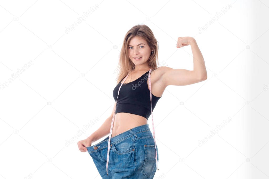 Slim young girl in big wide pants shows muscle on hand isolated  white background