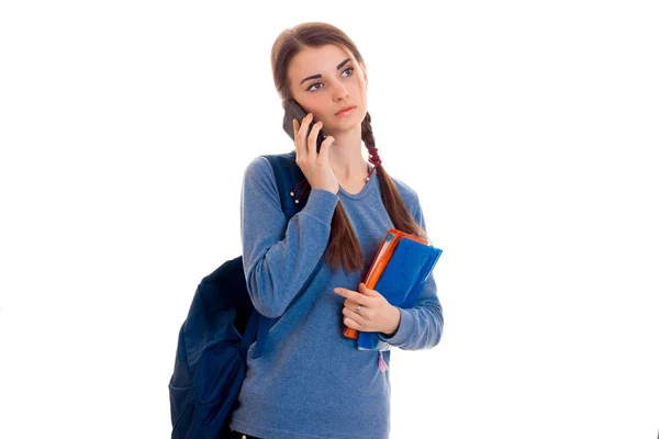 Hübsche junge brünette Studentin mit blauem Rucksack telefoniert isoliert auf weißem Hintergrund — Stockfoto