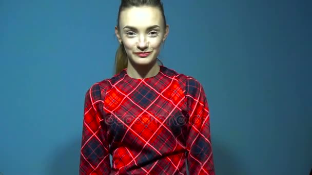 Schattige jonge dame in rode jurk gooien in de camera een pack van geld in slowmotion op blauwe achtergrond in de studio — Stockvideo