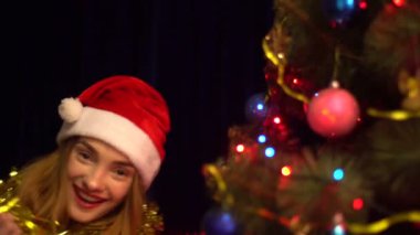 Noel Baba şapkası ile Noel ağacı dans ve gülümseyen mutlu genç kız