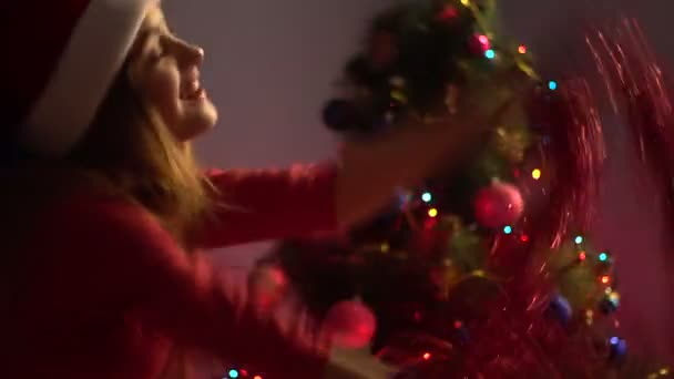 Boldog fiatal nő táncol a kezében talmi santa kalap. karácsonyi hangulatban — Stock videók