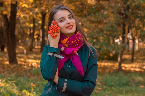 Menina bonita em um lenço rosa em torno de seu pescoço segura raminho de Rowan na mão e sorri — Fotografia de Stock