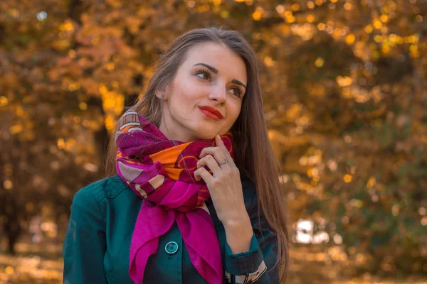 Aantrekkelijke jonge meisje staat in het park met een roze sjaal rond haar nek en ziet er weg — Stockfoto