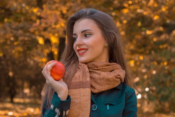 Beautiful girl with long hair and scarf looks away  holds an Apple in his hand, close-up — Stock Photo, Image