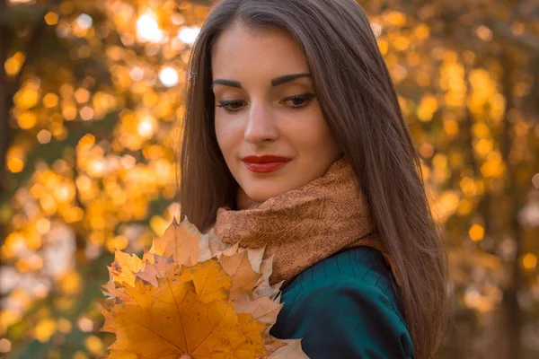 Portréja egy fiatal gyönyörű lány piros ajkak néz legyőz, és tartja a levelek közelről — Stock Fotó