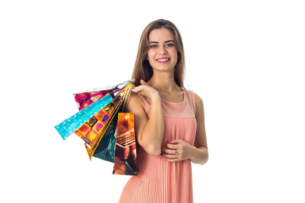 Sonriente joven se levanta recto mira hacia adelante y sostiene en su mano los diferentes paquetes con regalos se aísla sobre un fondo blanco — Foto de Stock