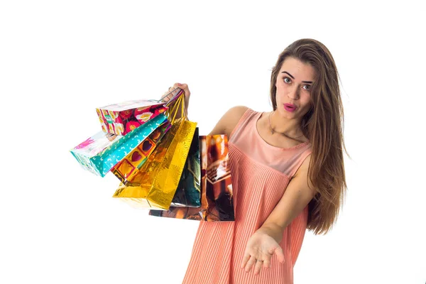 Divertida joven se inclinó hacia un lado y sostiene en su mano una gran cantidad de paquetes se aísla en el fondo blanco — Foto de Stock