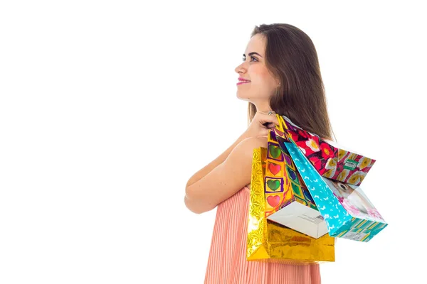 Jovem menina vale a pena virar de lado e mantém sacos de ombro coloridos brilhantes isolados no fundo branco — Fotografia de Stock